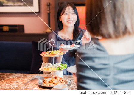 Two young women enjoying afternoon tea at a hotel 132351804