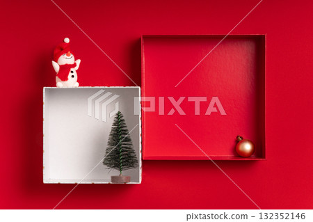 Festive red flat lay with two square box frames, a snowman and a tiny tree. Large copy space inside and around for text and mockups great for banners, headers, showcases and retail displays. 132352146