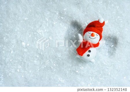 Flat lay of a snowman on artificial snow making a snow angel. Clean winter christmas background with copy space for posters, social media and winter fun concepts. Flat lay of a snowman on artificial snow making a snow angel. Clean winter christmas background with copy space for posters, social media and winter fun concepts. 132352148