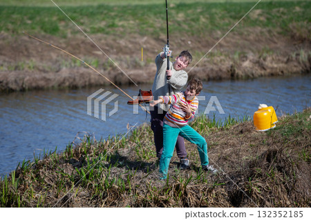 Funny fishing. Two of the boy's friends hooked an old shoe with a fishing rod and are laughing. Funny fishing. Two of the boy's friends hooked an old shoe with a fishing rod and are laughing. 132352185
