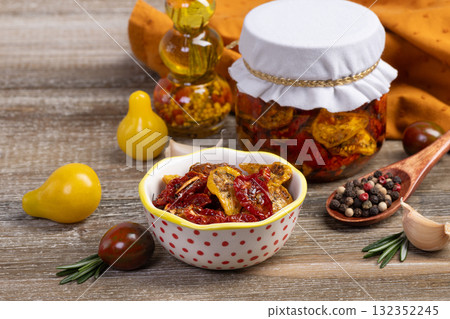Dried tomatoes in a jar and ingredients on the kitchen table. Dried tomatoes in a jar and ingredients on the kitchen table. 132352245