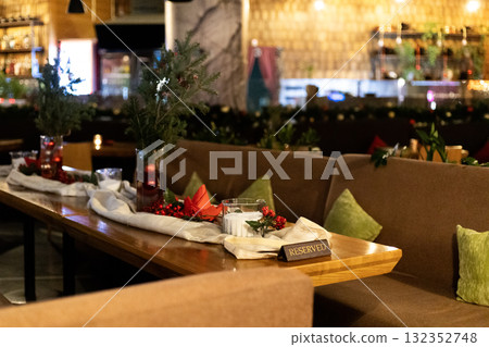 Christmas-decorated restaurant table with reserved sign and festive ornaments 132352748