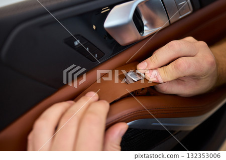 Skilled hands install a car door handle trim, highlighting craftsmanship and precision in design Skilled hands install a car door handle trim, highlighting craftsmanship and precision in design 132353006