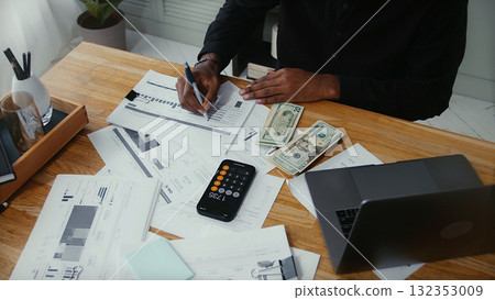 Hands reviewing finance charts with cash and calculator 132353009