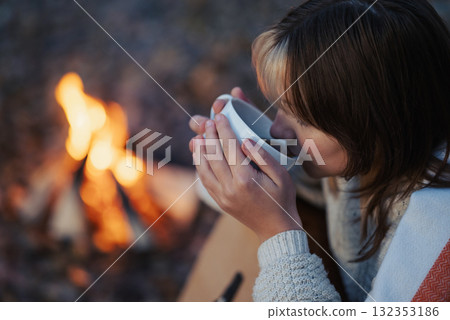 Young woman drinking tea or coffee playing the guitar near bonfire. Young girl having good time near campfire, playing the guitar, drinking warm beverage 132353186