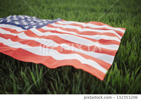 Flag of USA displayed on green winter wheat field in springtime. Toned image of vibrant USA flag waves over a lush winter wheat field, embodying spring and national pride 132353206