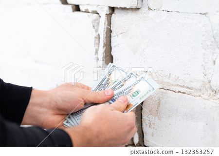 Building with a crack in wall. Man with dollar bills near the brick wall with big crack, concept of high price of repairing building 132353257