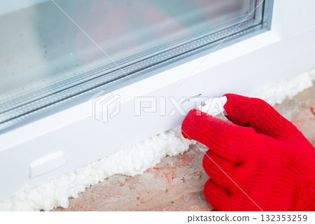 Installing new modern window. Hand of a worker installing plastic caps on condensation holes in window 132353259