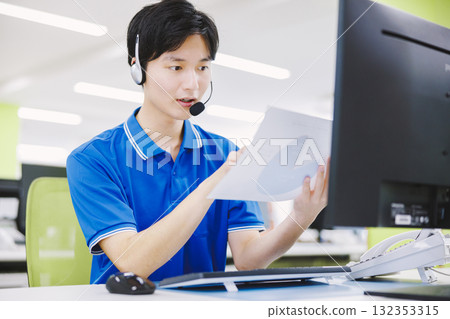 A man working in a call center wearing a headset 132353315