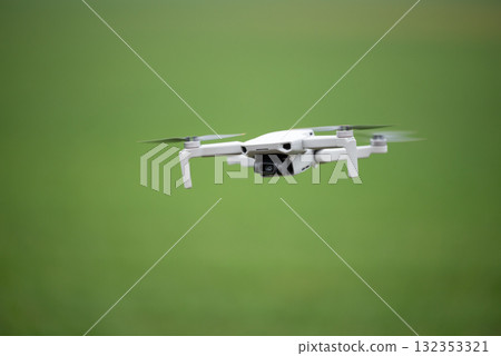 Small consumer drone in flight. Flying drone, recording video and shooting photos with build in camera Small consumer drone in flight. Flying drone, recording video and shooting photos with build in camera 132353321