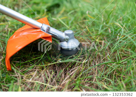 Close up of trimmer cutting grass. Mowing overgrown lawn, cutting grass with gasoline trimmer Close up of trimmer cutting grass. Mowing overgrown lawn, cutting grass with gasoline trimmer 132353362
