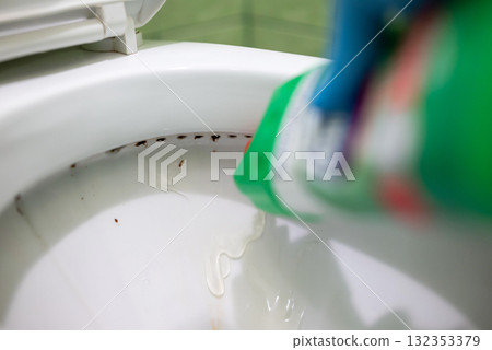 Applying washing gel to the toilet bowl under the rim. Cleaning toilet with powerful cleaning gel, keep toilet hygienic 132353379
