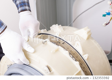 Washing machine service performed by a technician. A technician is repairing a washing machine drum by inspecting the inner components and making necessary adjustments Washing machine service performed by a technician. A technician is repairing a washing machine drum by inspecting the inner components and making necessary adjustments 132353392