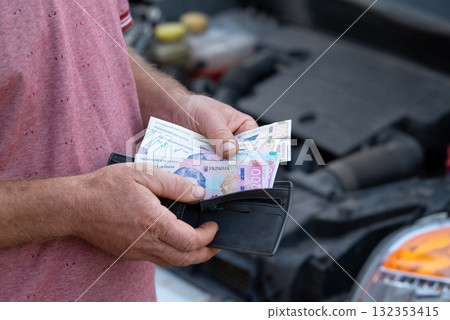 Ukrainian counting hryvnias to pay for car service. Driver spending money for fixing broken down car Ukrainian counting hryvnias to pay for car service. Driver spending money for fixing broken down car 132353415