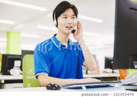 一名戴著耳機在呼叫中心工作的男子 一名戴著耳機在呼叫中心工作的男子 132353474