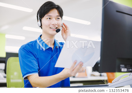 一名戴著耳機在呼叫中心工作的男子 一名戴著耳機在呼叫中心工作的男子 132353476