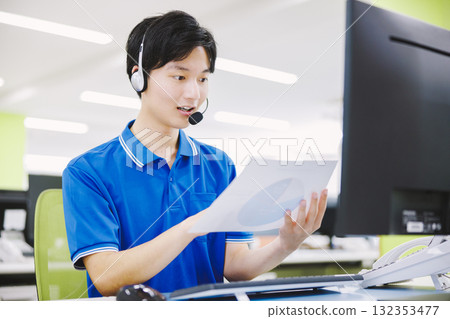 A man working in a call center wearing a headset A man working in a call center wearing a headset 132353477