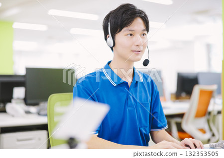 A man working in a call center wearing a headset A man working in a call center wearing a headset 132353505