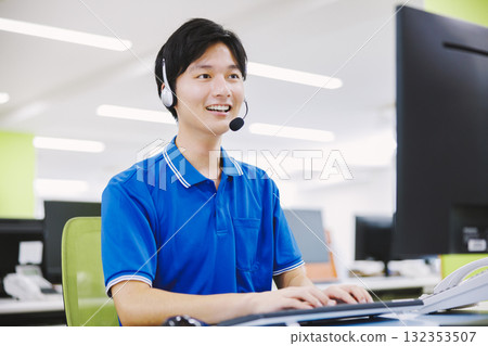 A man working in a call center wearing a headset A man working in a call center wearing a headset 132353507