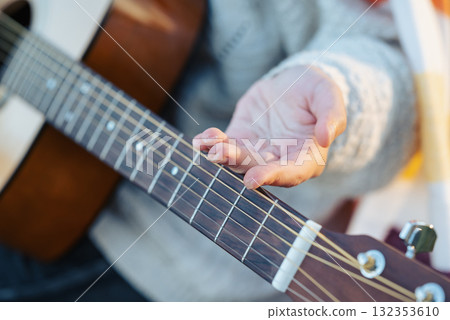 Girl shows callus on her fingers after playing the guitar for a long time. Close up of young female guitaris practicing instrument on nature on a cool sunny weather 132353610