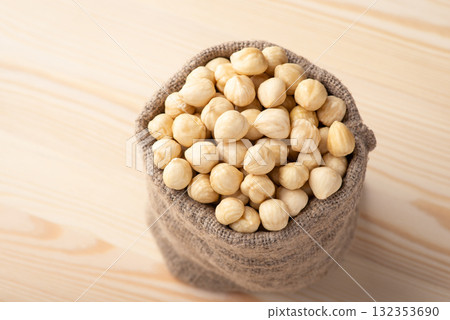 Small linen bag with hazelnuts on wooden background. Tasty peeled hazelnuts Small linen bag with hazelnuts on wooden background. Tasty peeled hazelnuts 132353690