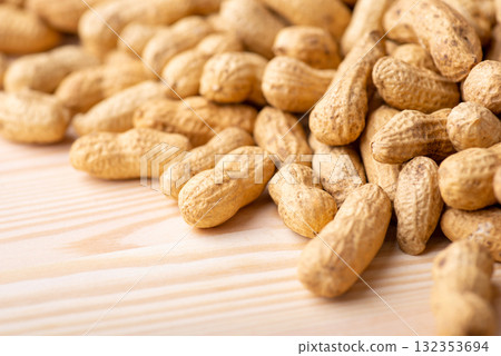 Some peanuts in shell on wooden table. Close up of unpeeled peanuts background Some peanuts in shell on wooden table. Close up of unpeeled peanuts background 132353694