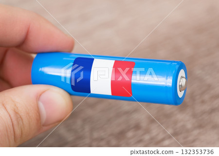 Rechargeable battery with flag of France in hand of a man. Production of batteries in France concept 132353736