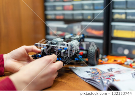 Kid making robot toy car following the instructions. Boy playing with developing kit for young engineers Kid making robot toy car following the instructions. Boy playing with developing kit for young engineers 132353744