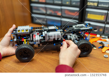 Ready model made of an engineering constructor on the table. Machine toy with motors and complex mechanisms made by small engineer Ready model made of an engineering constructor on the table. Machine toy with motors and complex mechanisms made by small engineer 132353748