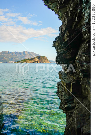 View of the Adriatic Sea near Budva, Montenegro, with a coastal rock occupying half of the frame. Scenic seascape with natural rock formations and calm waters. View of the Adriatic Sea near Budva, Montenegro, with a coastal rock occupying half of the frame. Scenic seascape with natural rock formations and calm waters. 132353890