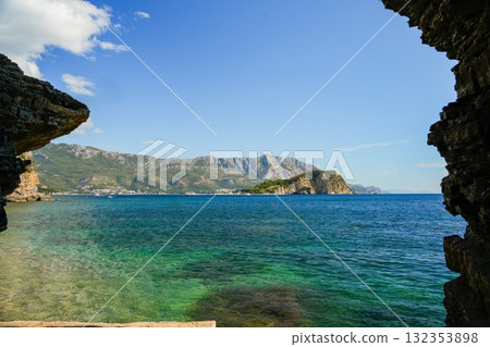 View of the Adriatic Sea in Budva, Montenegro, framed by rocky cliffs on both sides. Scenic coastal landscape with natural rock formations and clear water. View of the Adriatic Sea in Budva, Montenegro, framed by rocky cliffs on both sides. Scenic coastal landscape with natural rock formations and clear water. 132353898