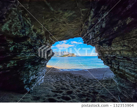 Entrance of a seaside cave frames the Adriatic Sea with Hawaii Island in the distance near Budva, Montenegro. Peaceful marine landscape. 132353904