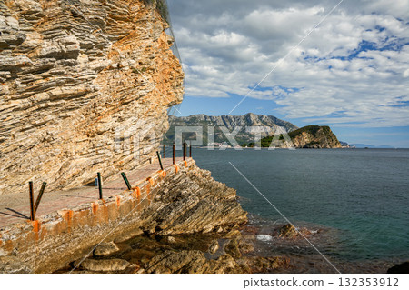 View of a coastal path along rocky cliffs with the Adriatic Sea in Budva, Montenegro. Scenic nature and seaside trail. 132353912