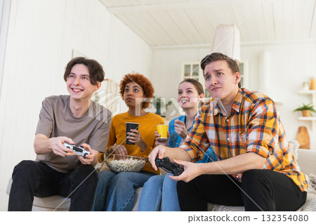 Home party. Cheerful group of friends playing video games at home. Happy diverse group buddies having fun together indoor. Friendship leisure entertainment concept. Young best friends enjoying weekend 132354080