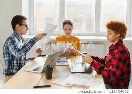 Teamwork brainstorm. Diverse colleagues working together discuss financial statistics. Group of happy young modern people sitting in creative office discussing business. Young professional team 132354092