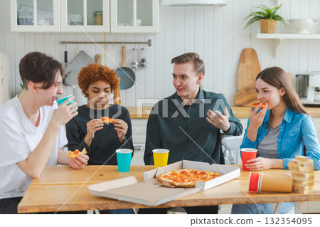 Home party. Overjoyed diverse friends eating ordered pizza for home party. Happy group multiracial young buddies enjoying spending free weekend time together having fun laughing joking communicating 132354095