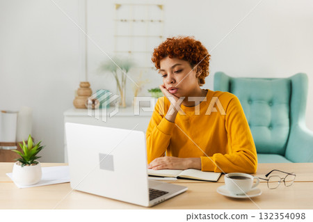 Sleepy sad African American woman sitting at table with laptop. Tired overworked girl lazy to work. Student businesswoman relaxing bored in home office after work on laptop computer Sleepy sad African American woman sitting at table with laptop. Tired overworked girl lazy to work. Student businesswoman relaxing bored in home office after work on laptop computer 132354098