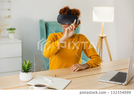 African American young woman wearing using virtual reality metaverse VR glasses headset at home. Girl touching air during VR experience on virtual reality helmet. Simulation hi-tech videogame concept African American young woman wearing using virtual reality metaverse VR glasses headset at home. Girl touching air during VR experience on virtual reality helmet. Simulation hi-tech videogame concept 132354099