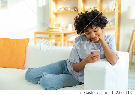 African girl holding smartphone touch screen typing scroll page at home. Woman with cell phone surfing internet using social media apps playing game. Shopping online Internet news cellphone addiction African girl holding smartphone touch screen typing scroll page at home. Woman with cell phone surfing internet using social media apps playing game. Shopping online Internet news cellphone addiction 132354118