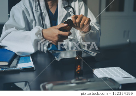 Female doctor holding a medicine bottle is checking the quality of medicine for any side effects the patient or not and recording patient information at the hospital. medical and health care concept 132354199