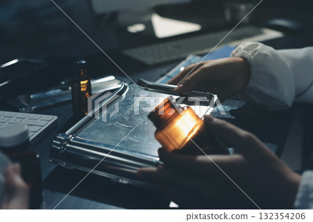 Female doctor holding a medicine bottle is checking the quality of medicine for any side effects the patient or not and recording patient information at the hospital. medical and health care concept 132354206