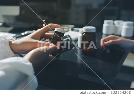 Female doctor holding a medicine bottle is checking the quality of medicine for any side effects the patient or not and recording patient information at the hospital. medical and health care concept 132354208