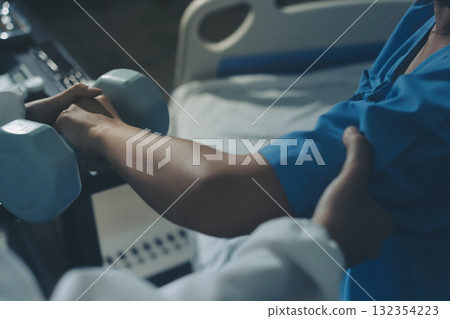 Physical therapist assisting a woman with dumbbell exercise 132354223