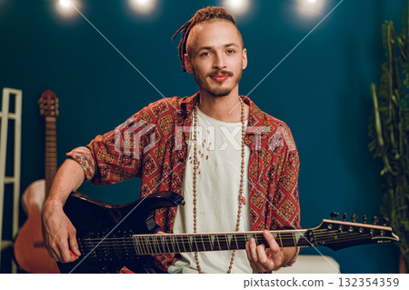 Young man guitar player sitting and performing on a couch 132354359