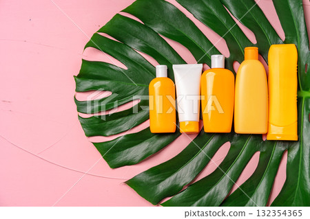 Many bottles with sunscreen skincare products and monstera leaf on pink background. Sun protection cosmetics concept 132354365