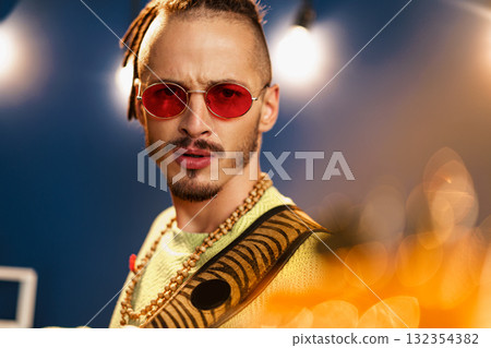 Young fashionable man in pink sunglasses playing guitar with joy Young fashionable man in pink sunglasses playing guitar with joy 132354382
