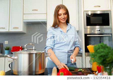 Young woman cutting vegetables for salad in kitchen Young woman cutting vegetables for salad in kitchen 132354418