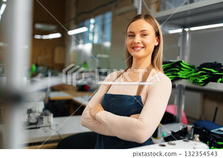 Portrait of a seamstress standing at working place and looking at camera Portrait of a seamstress standing at working place and looking at camera 132354543