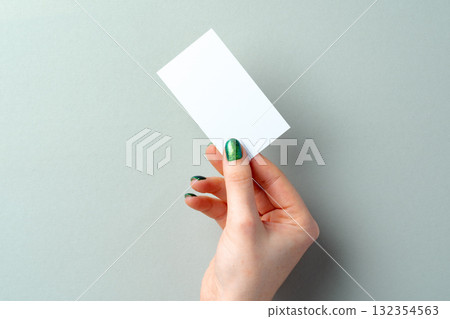 Woman's hand with manicure holding white business card above the table Woman's hand with manicure holding white business card above the table 132354563
