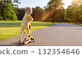 Child riding. Scooter toddler park play. Summer road motion casual sport. 132354646